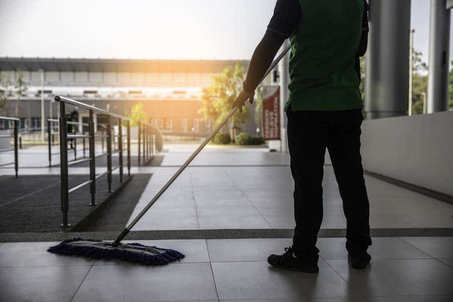 cleaner with mop and uniform cleaning hall floor of public busin Cleaning Event Venue